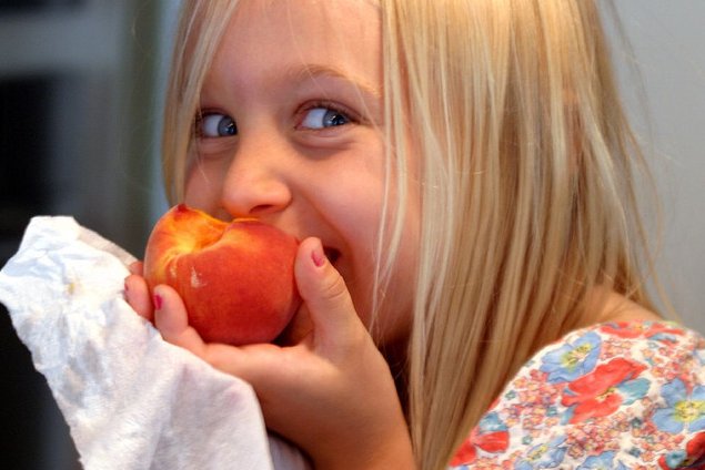 Niña comiendo un melocotón